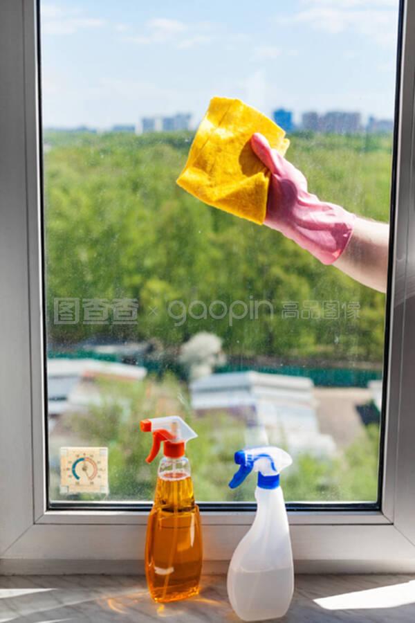 阳光明媚的日子里,她用抹布清洁窗户玻璃